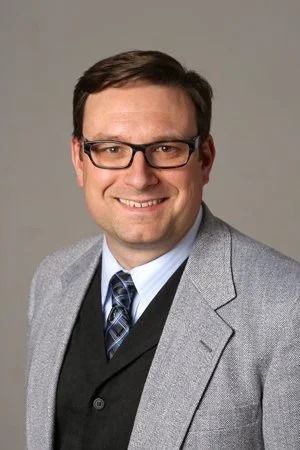 Matt Koncar, owner of Rose Hill, smiling in a gray blazer and tie