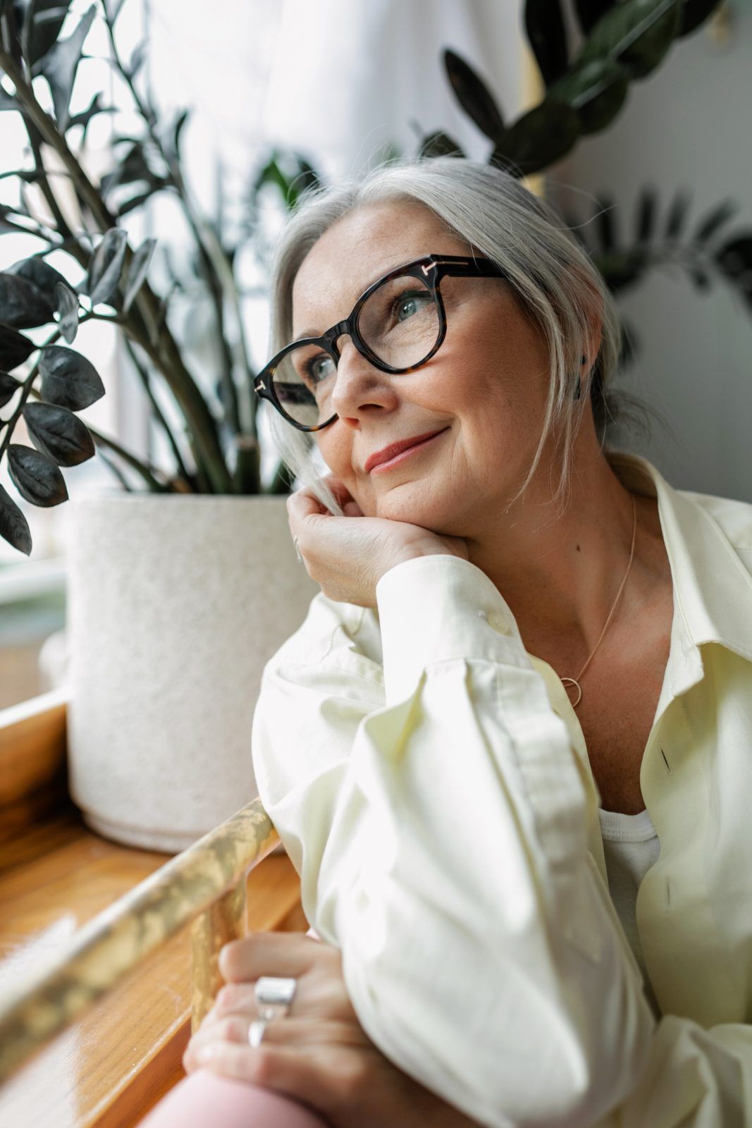 Older woman with glasses smiling as she looks out a window